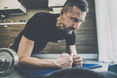 Sporty man working out and trains at home. fit boy doing exercises on the mat in the living room. 