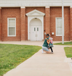 Young millennial mother sending daughter off back to school