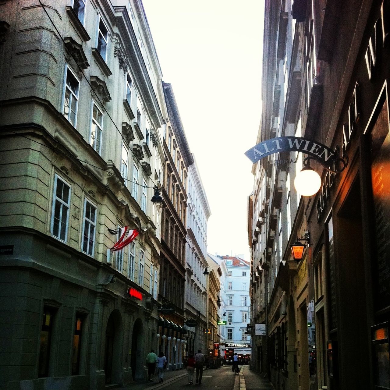 architecture, building exterior, built structure, transportation, street, car, city, land vehicle, building, mode of transport, city life, city street, road, incidental people, clear sky, residential building, low angle view, the way forward, window, street light