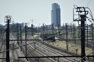 Railroad tracks by buildings in city against sky