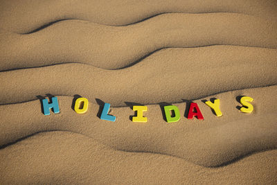 Holidays written out on wooden letters text on sand of a dune