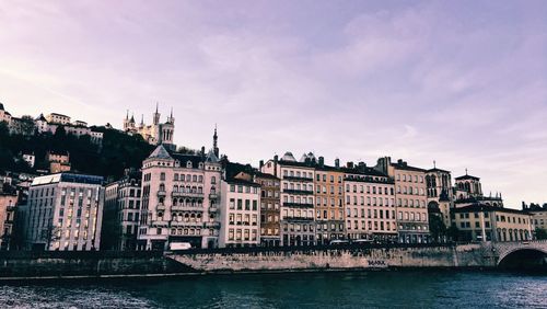 River by buildings against sky