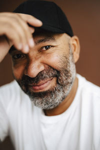 Portrait of smiling mature man holding cap in studio