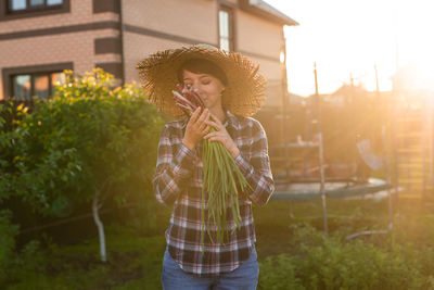 Woman smelling vegetable while standing outdoors