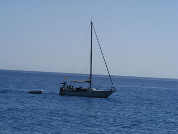 Boat sailing on sea against clear sky