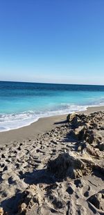 Scenic view of beach against clear blue sky