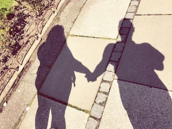 High angle view of people shadow on cobblestone