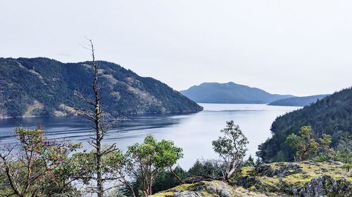 Scenic view of sea and mountains against clear sky