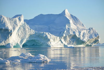 Scenic view of sea and snowcapped mountains against sky