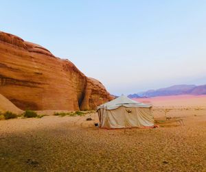 Tent on sand dune against clear sky