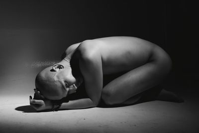 Portrait of shirtless boy lying against gray background