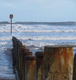 Wooden posts on beach against sky