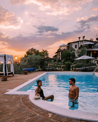 Rear view of couple in swimming pool against sky