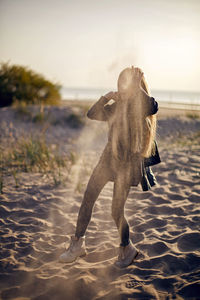 Portrait of a girl with long hair run on a sandy beach in a black leather jacket