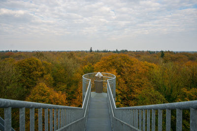 Footbridge over trees against sky during autumn