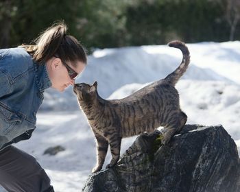 Woman playing with cat on snowy field