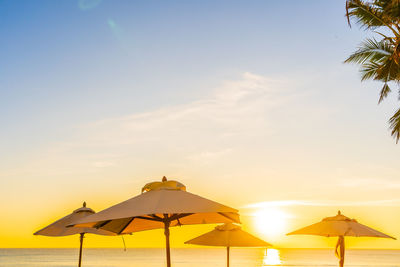 Umbrellas on beach against sky during sunset