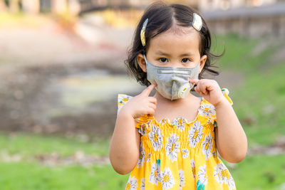 Cute girl standing outdoor wearing medical face mask to prevent flu, pollution and covid 19.
