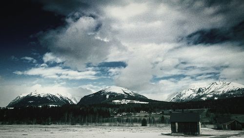 Scenic view of snow covered mountains against cloudy sky