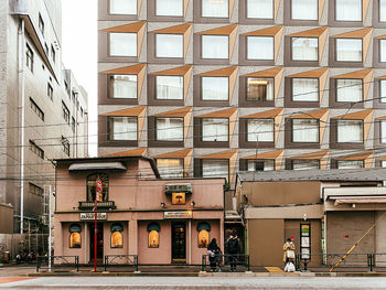 People on street by building in city