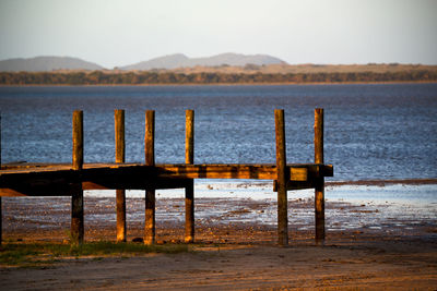 Wooden posts on beach against sky