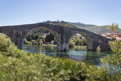 Arch bridge over river against clear sky