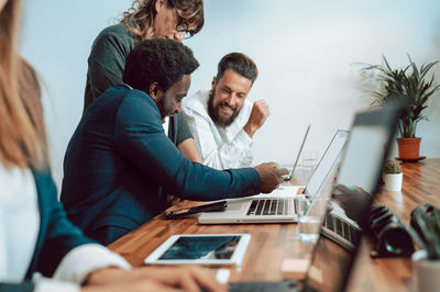 Content diverse coworkers examining papers near laptops