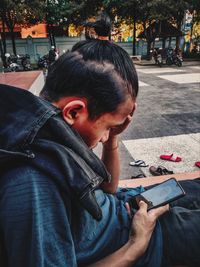 Portrait of man using mobile phone while sitting on street