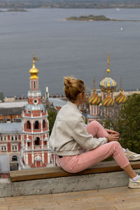 Side view of woman sitting on retaining wall