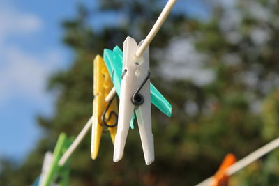 Close-up of clothespins hanging on clothesline against sky