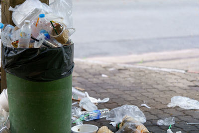 Image of plastic trash filled with trash that overflows outside.