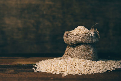 Natural raw unpolished brown rice in burlap sack on wooden table