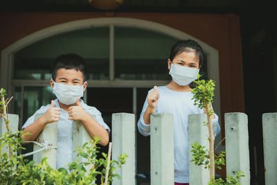 Portrait of smiling sibling wearing mask standing outdoors