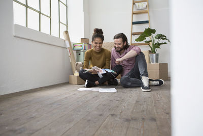 Couple sitting on floor of new flat choosing from color samples