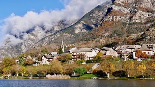 Houses by lake and mountains against sky