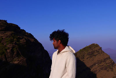 Young man standing on rock against mountain