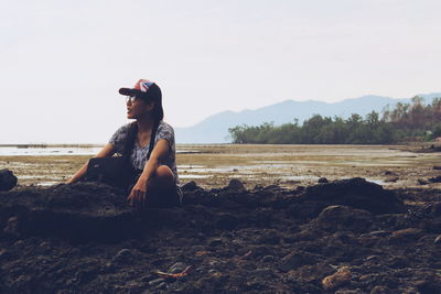 Young woman at beach against clear sky