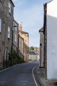 Empty road amidst buildings against sky