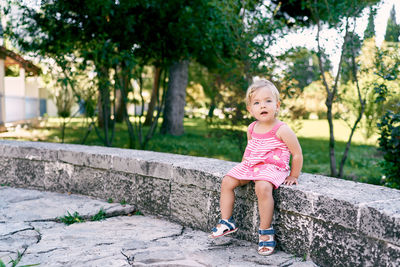 Full length of woman sitting against trees