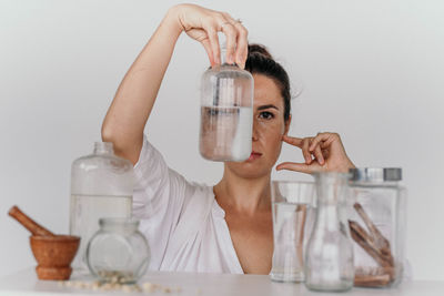 Close-up of scientist holding bottle against white background