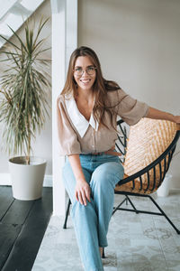 Portrait of young woman sitting on chair at home