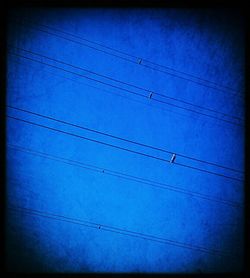 Low angle view of power lines against blue sky