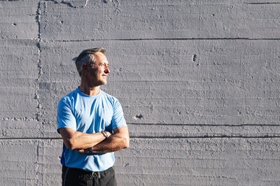 Young man looking away against wall