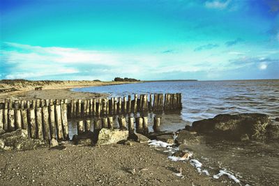 Pier on sea against cloudy sky