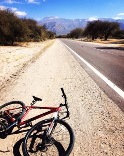 Bicycle parked by road on sunny day