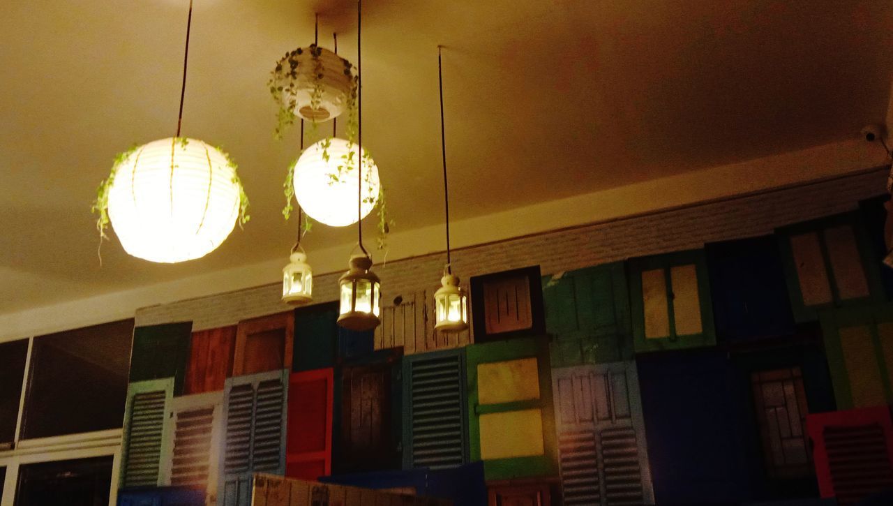 LOW ANGLE VIEW OF ILLUMINATED PENDANT LIGHTS HANGING ON CEILING