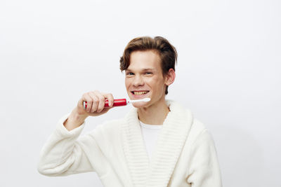 Portrait of smiling young woman holding bottle against white background