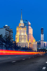 Light trails on road against buildings in city at dusk