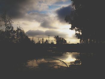 Silhouette of trees against cloudy sky at sunset