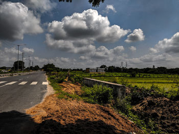 Road amidst field against sky